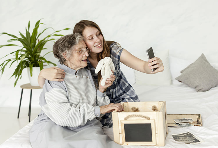 Carmen’s story and how accessibility changed her home 3 The granddaughter and Carmen take a photo together with a mobile phone on a bed