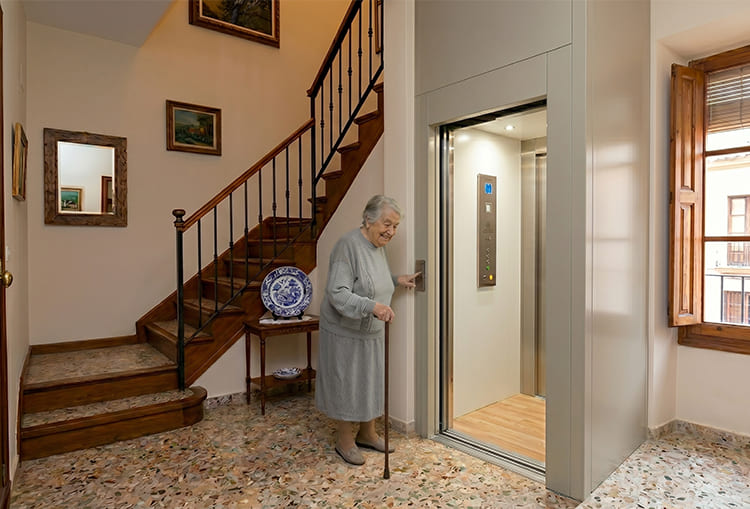 L’histoire de Carmen et comment l’accessibilité a transformé son foyer 2 Carmen sourit en appuyant sur le bouton d'un ascenseur unifamilial installé à côté d'un escalier en bois