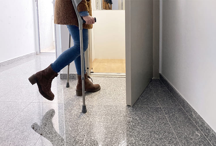 Los ascensores que mejor aprovechan el espacio en tu hogar 3 Persona utilizando muletas al ingresar a un ascensor residencial adaptado para movilidad reducida