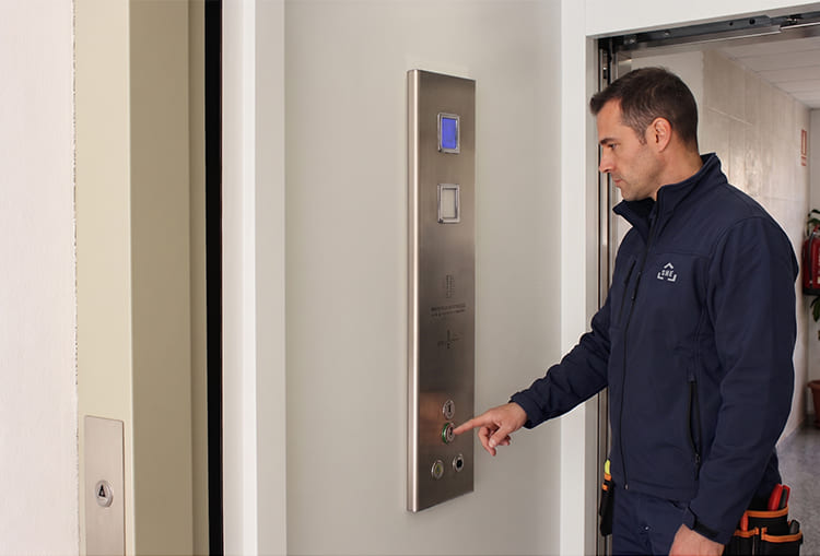 Comment se déroule l’entretien d’un ascenseur privatif ? 3 Technicien réalisant le test final de fonctionnement sur le panneau de commande d'un ascenseur privatif